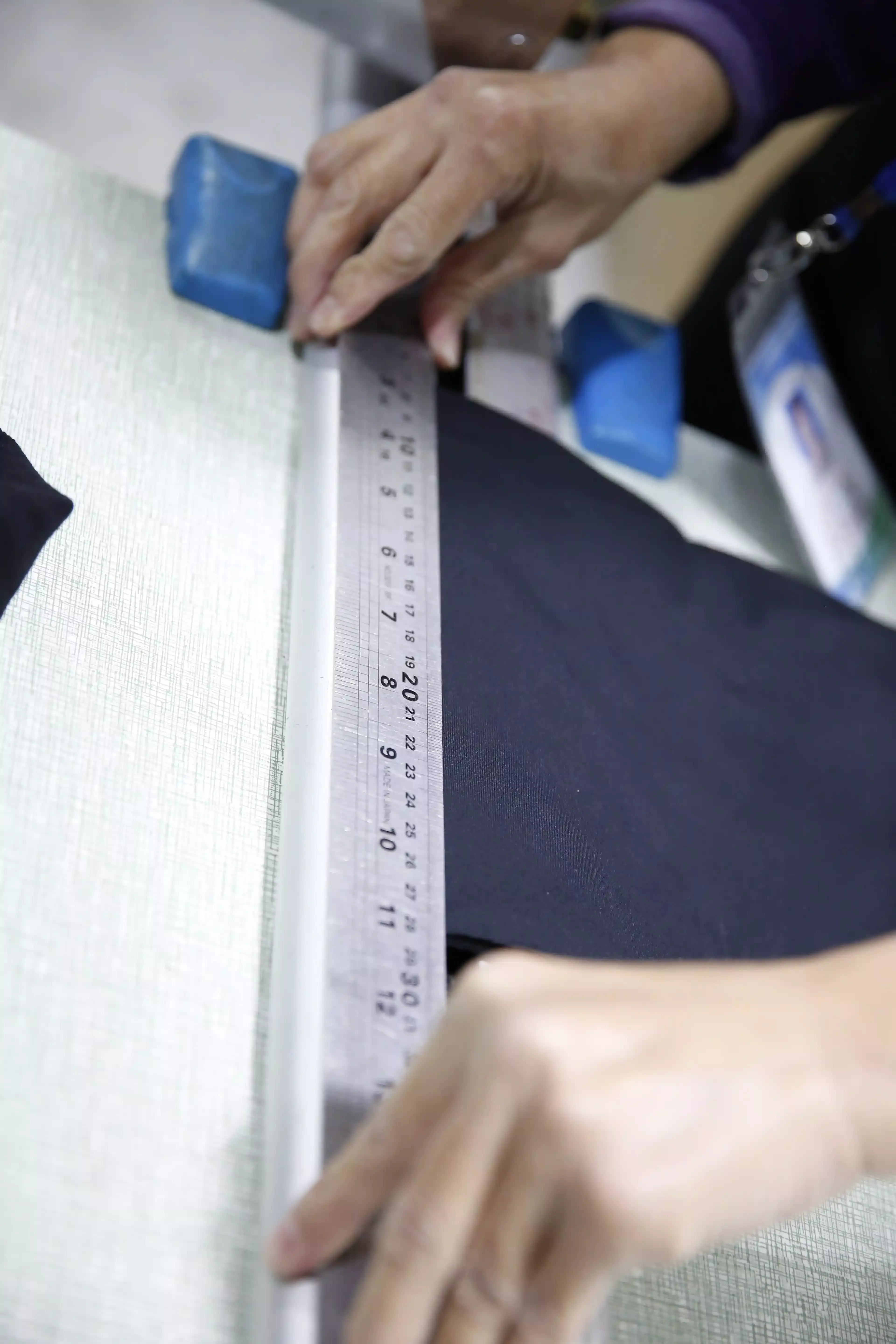 Quality controller measuring period underwear dimensions with a steel ruler